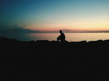 Silhouette man standing on beach against sky during sunset