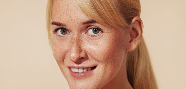 Close-up portrait of young woman against pink background