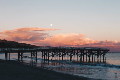 Pier over sea against sky during sunset