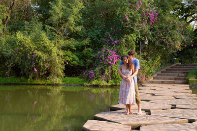 Couple standing by tree on lake