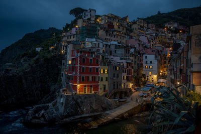 Illuminated buildings in town against sky at dusk