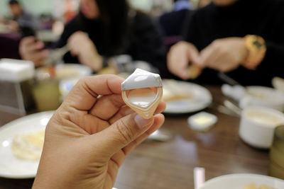 Midsection of person holding drink in glass on table