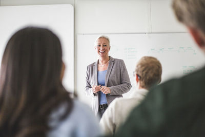 Smiling mature female teacher teaching in university classroom