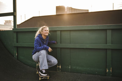 Smiling teenage girl crouching on skateboard