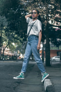 Portrait of young woman standing against tree