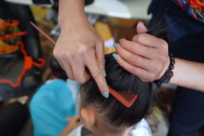 Midsection of mother combing hair of daughter at home