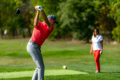 Young couple on a golfing vacation, man teeing off