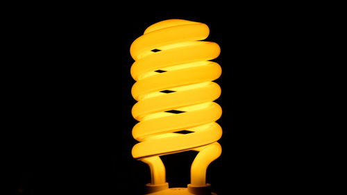 Low angle view of illuminated light bulb against black background