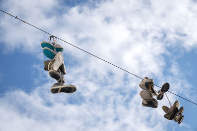 Low angle view of shoes hanging on rope against sky