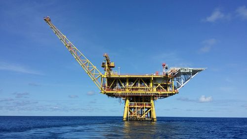 Crane by sea against sky