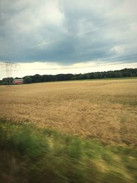 Scenic view of field against cloudy sky