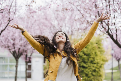 Young woman standing on cherry blossom tree