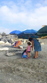 People on beach against cloudy sky