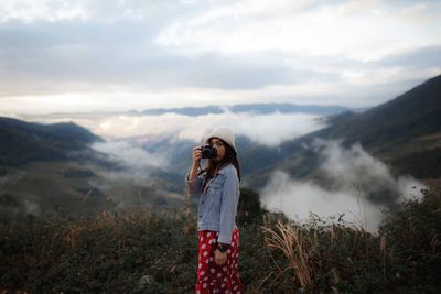 Woman standing on mountain against sky