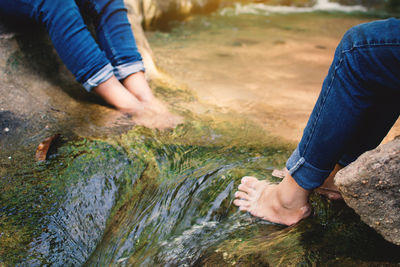 Low section of people sitting in rocky stream