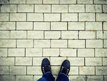 Low section of man standing on brick wall