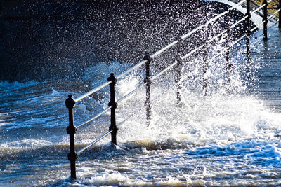 Water splashing on railing against sea