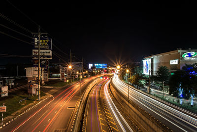 Light trails on road in city against sky at night
