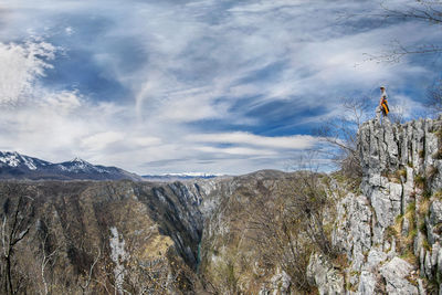 Woman standing on cliff against sky