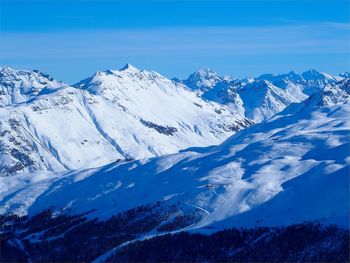 Scenic view of snowcapped mountains against blue sky