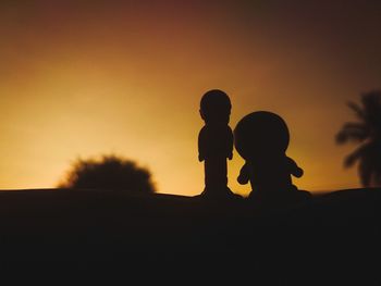 Silhouette children standing against sky during sunset