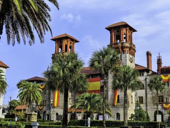 Low angle view of historic building and palm tree against sky