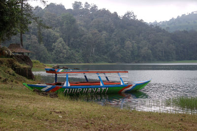 Boat moored on river by mountains
