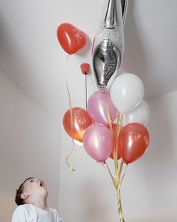 Happy boy looking at helium balloons at home