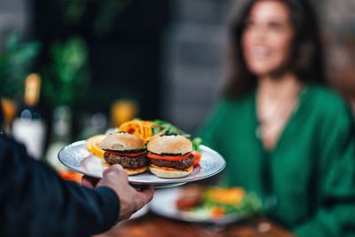 Cropped hand of waiter keeping food on table in restaurant