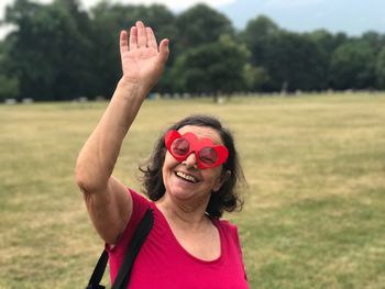 Portrait of mature woman wearing heart shape novelty glasses on field