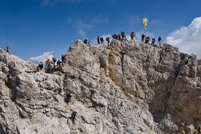 Low angle view of people on rock against sky