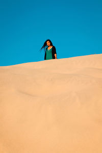 Man standing in desert against clear blue sky