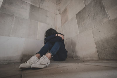 Full length of woman sitting on wall