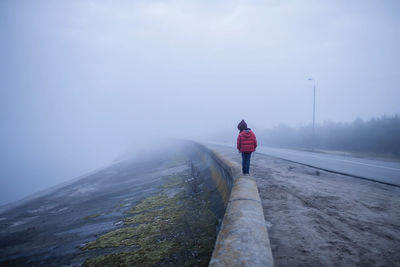 Rear view of man standing on snow against sky