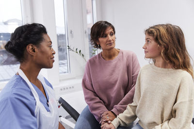 Female doctor talking to girl patient and mother during appointment