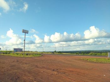 Road passing through agricultural field against sky