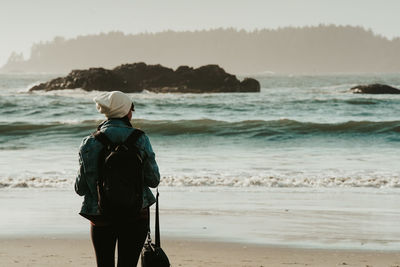 Rear view of woman standing at beach