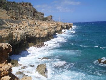 Scenic view of sea by cliff against sky