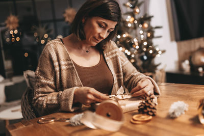 Good mood woman in a cozy environment wrapping gifts for christmas, stylish decoration, vintage