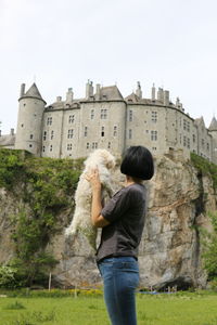 Woman carrying dog against castle