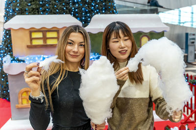 Couple of young multi-ethnic women eating cotton candy at a party. concept of millennial generation