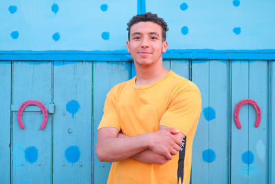 Portrait of smiling young man standing against blue wall