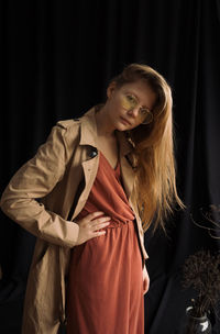 Young woman standing against curtain