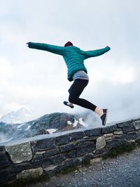 Full length of woman jumping against sky during winter