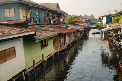 Houses by canal in town against sky