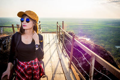 Woman standing by railing against sky