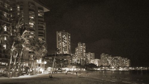 Illuminated buildings against sky at night