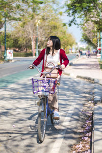 Full length of woman riding bicycle on road