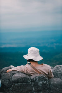 Rear view of man sitting against sky