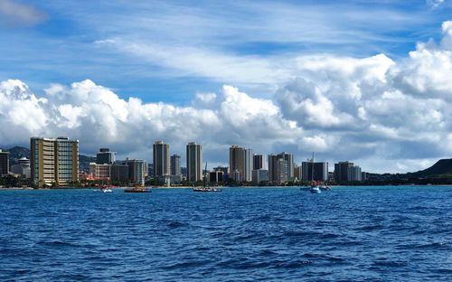 Sea by city buildings against sky